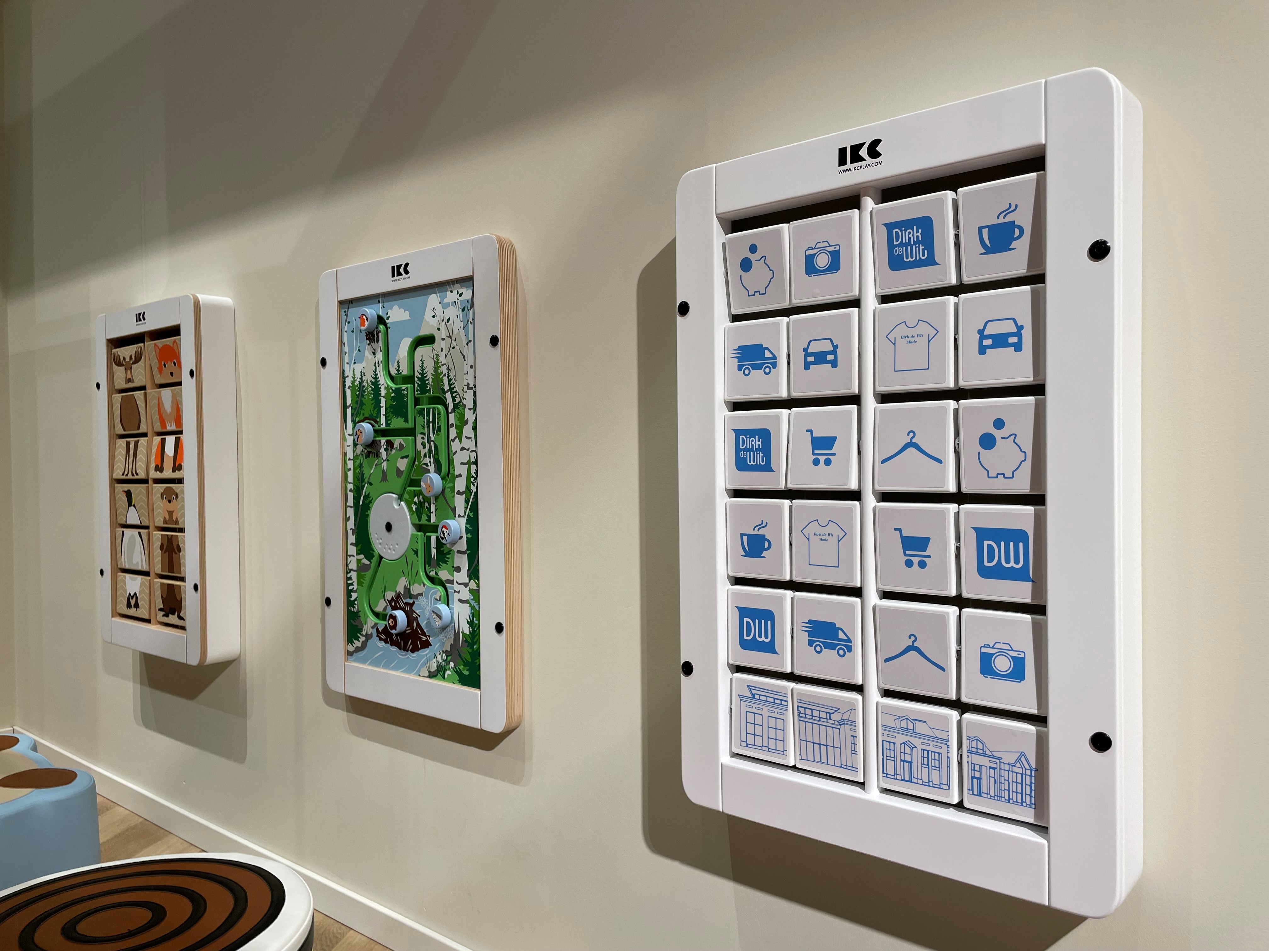 Soft-Play Kids' Corner with Wall-Mounted Games – IKC Concept Children’s corner with interactive wall play panels and soft seating in a public waiting area